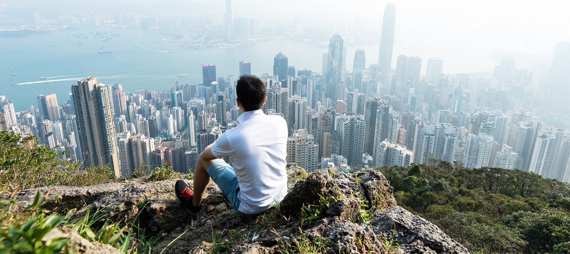 Men sitting on the top of mountain and looking cityscape